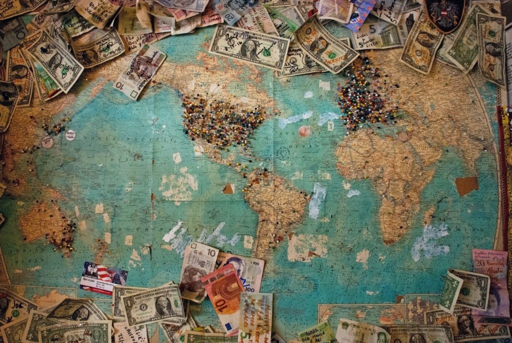 a map of the world with pins stuck in at different locations and different currencies pinned to the map with notes written on the bills