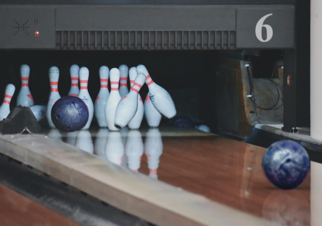 close up of blue bowling balls on a lane knocking over pins