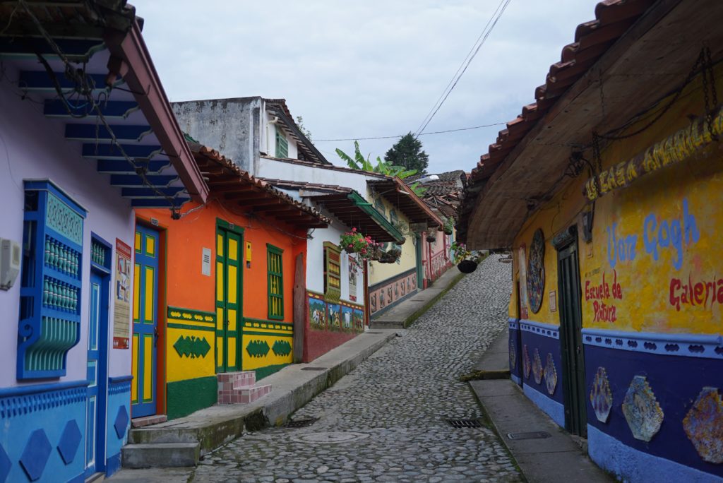 View looking up a cobblestone road with brightly colored buildings on either side 