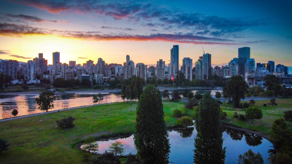 Fun places to go with friends include Vancouver- view looking towards the skyline from above over a park with trees and the river