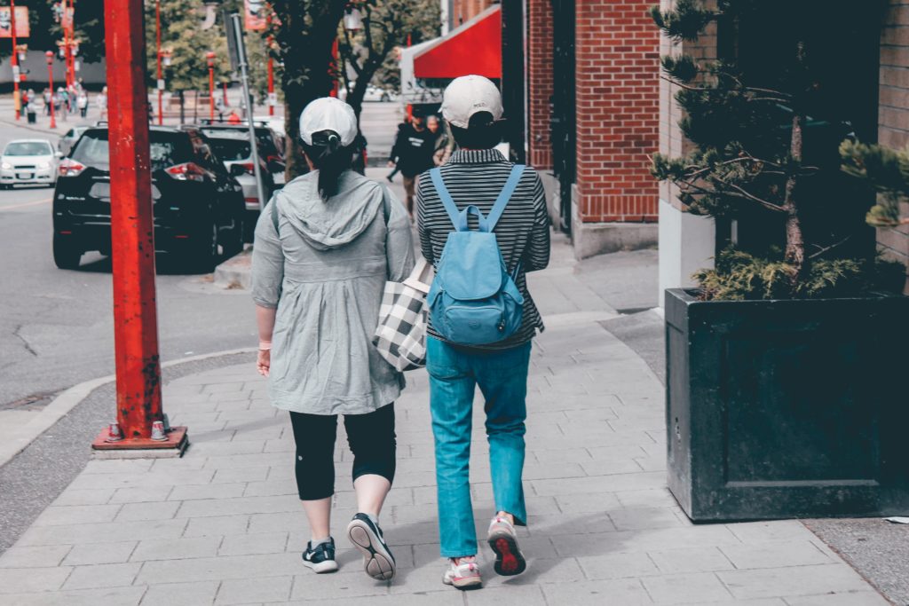 two women walking through Chinatown from behind 