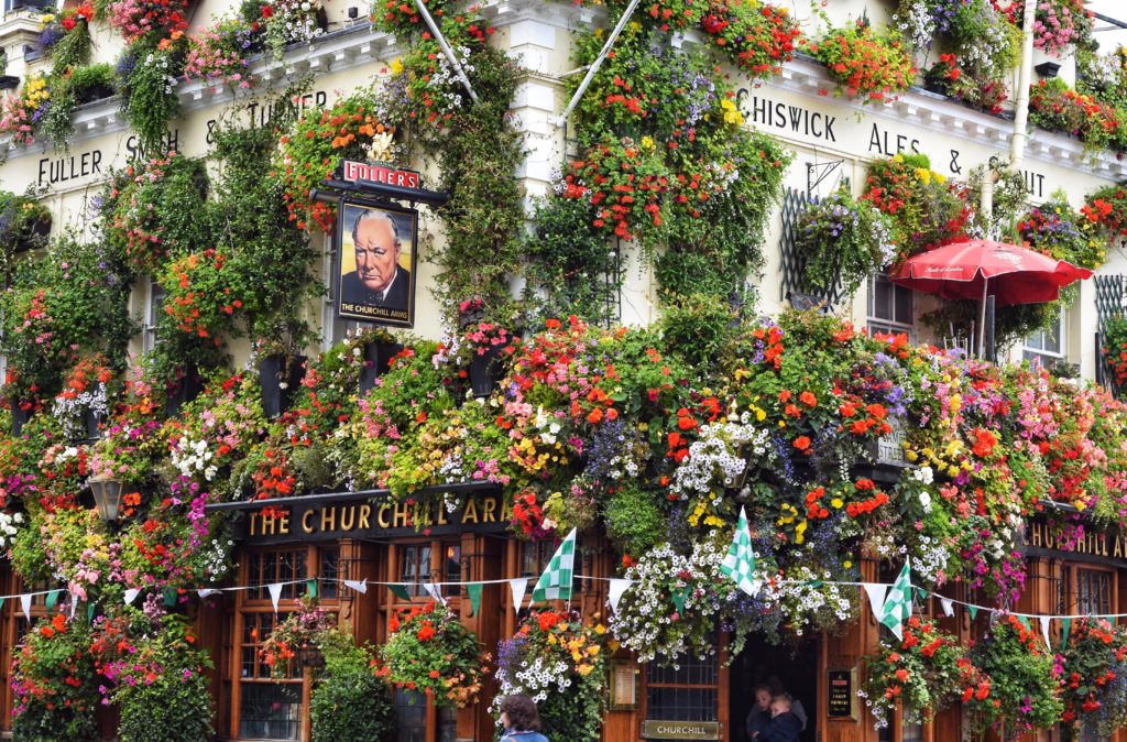 Outside view of The Churchill Arms bar in London covered in colorful flowers 