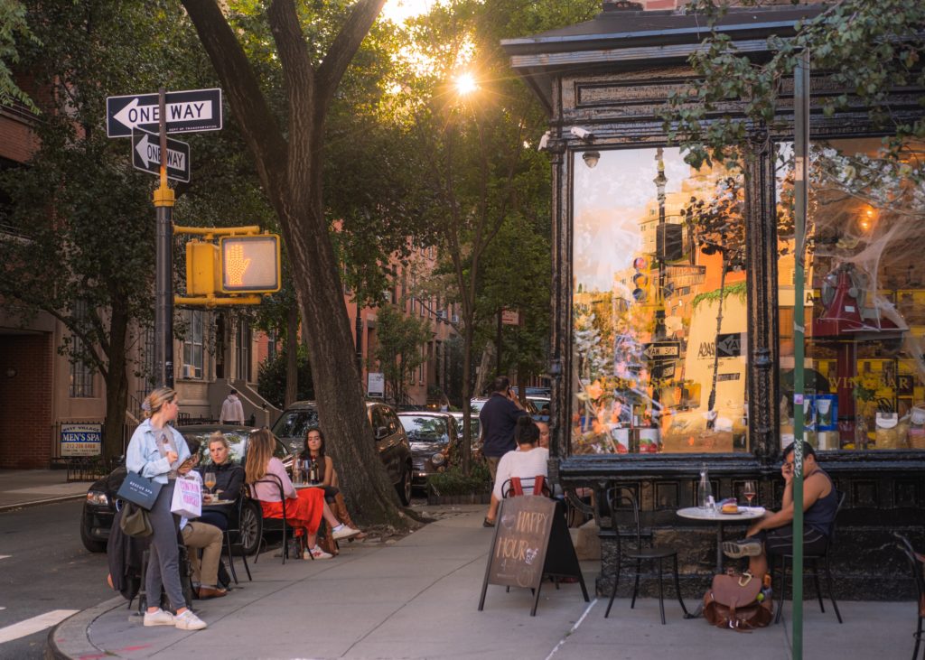 50th birthday trip ideas- New York City street corner with people city outside at a cafe