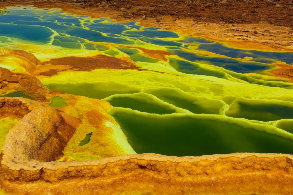 neon yellow, orange, green, and blue pools of geothermal activity
