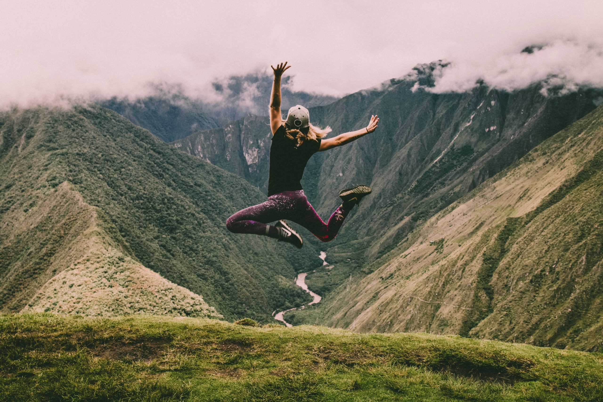 Landscape image of a woman jumping for joy with the Peruvian Andes in the background