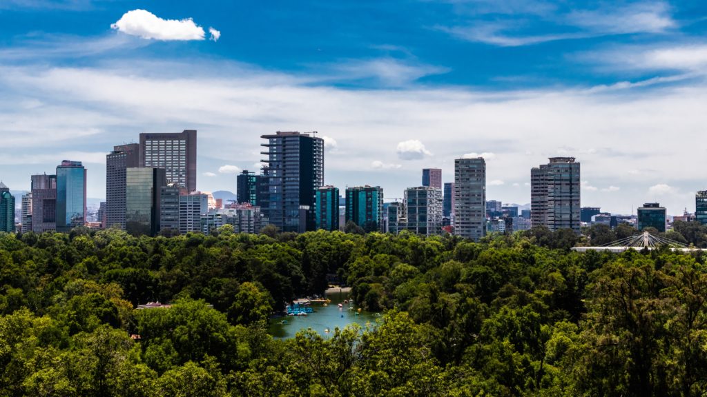 View of trees and a lake in Chapultepec Park with Mexico City's skyscrapers in the background