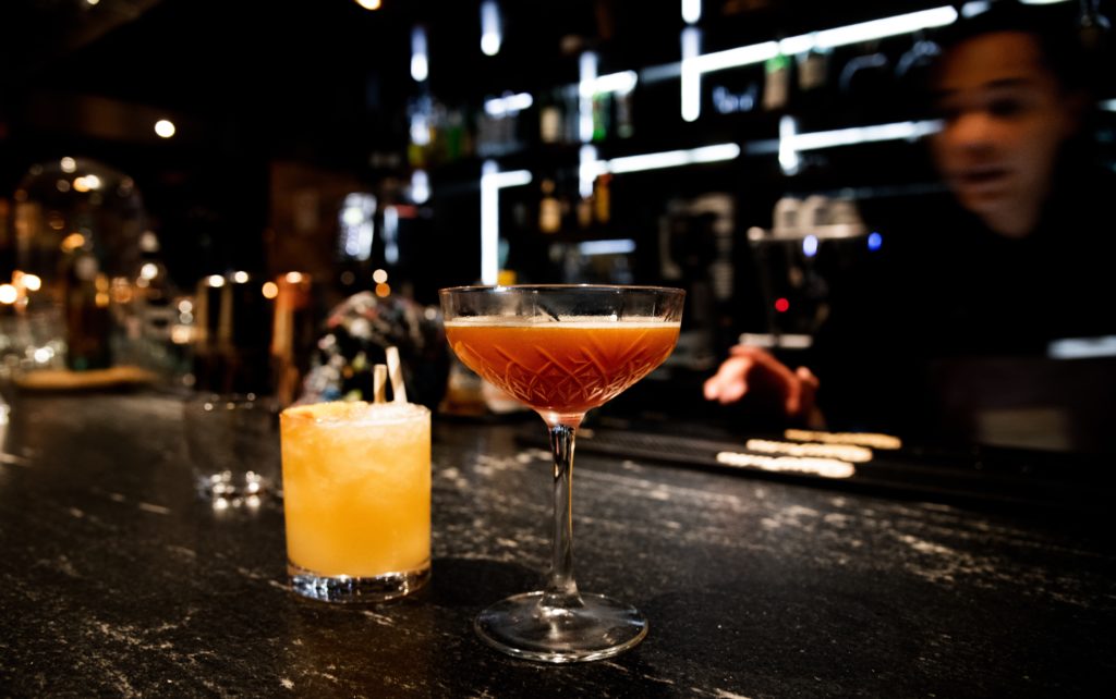 two cocktails sit on a dark bar in Roma Norte