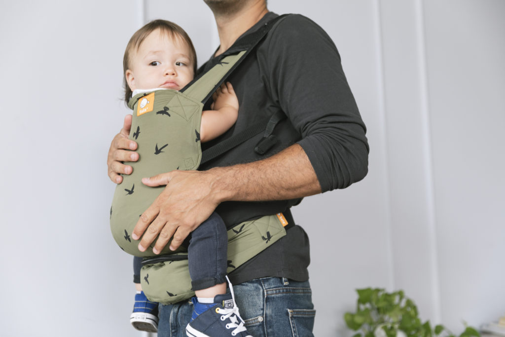 baby sitting in a tula lite carrier - one of the top baby travel essentials