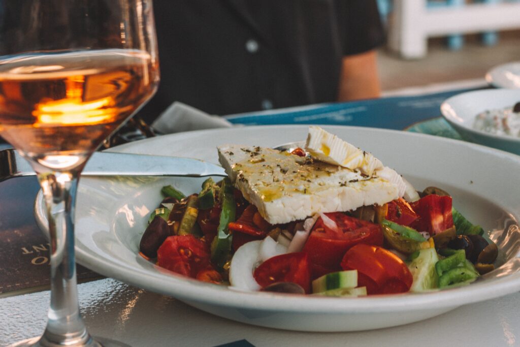 greek salad topped with feta next to a glass of rose wine. Greece family vacation cooking class with kids